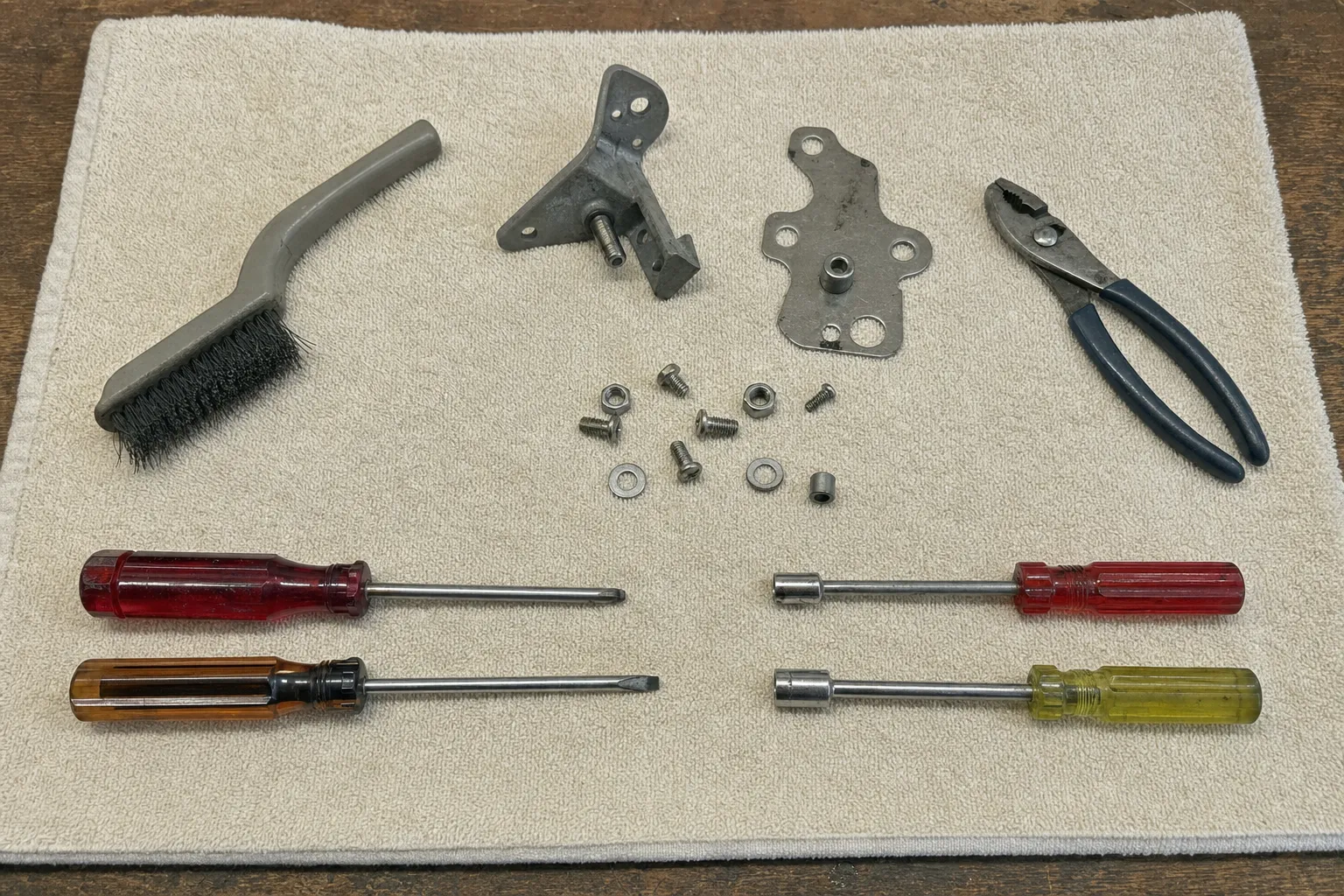 Nut drivers, pliers, a parts brush and door hardware laid out before a dishwasher repair