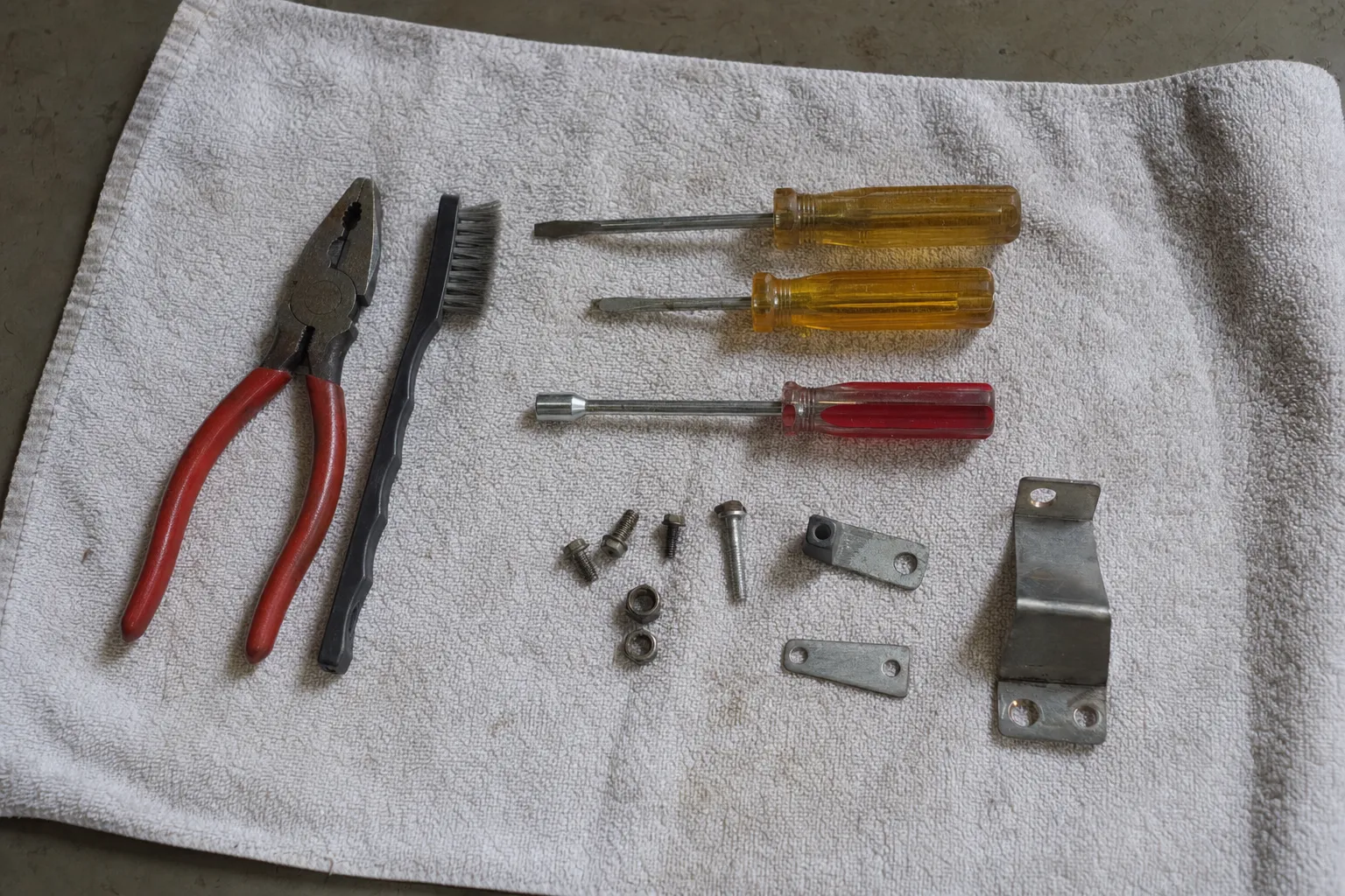 Pliers, screwdrivers, a wire brush and mounting brackets laid out on a towel ahead of a service call